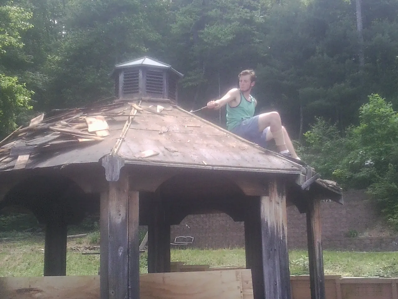 Tearing the old roof off a wooden gazebo before new shakes in Florence